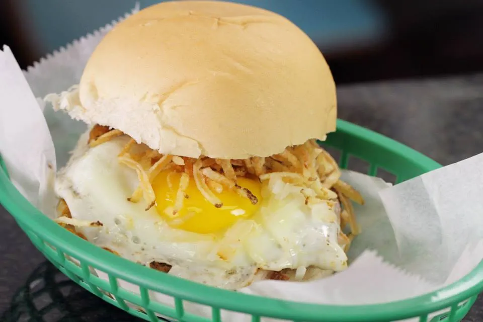 Frita a caballo: Cuban frita topped with a fried egg and crispy shoestring potatoes in a green basket